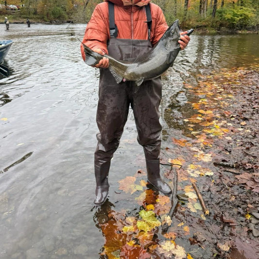 Angler wearing 8808 expandable fishing backpack holding large salmon catch by autumn lakeside