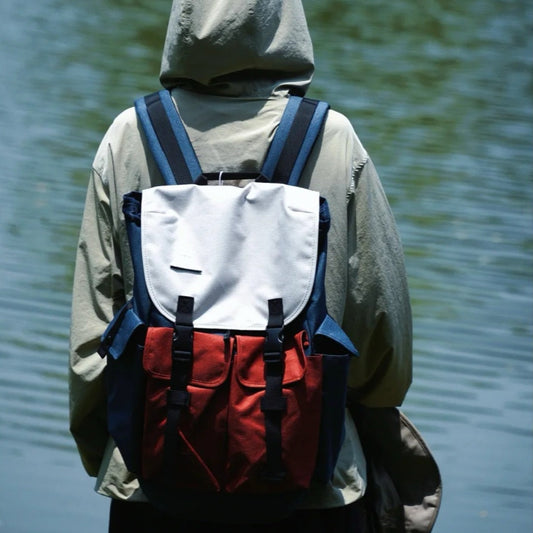 Front view of canvas backpack showing organizational pockets and color-block design