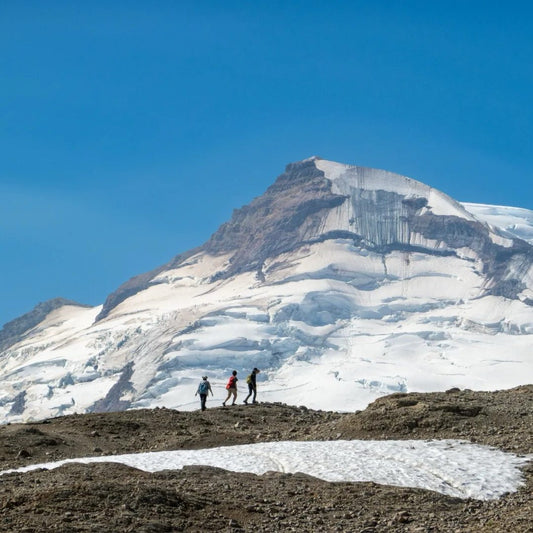 Three female hikers in technical women's hiking outfits traversing glacial terrain, showing proper gear selection for challenging mountain conditions"