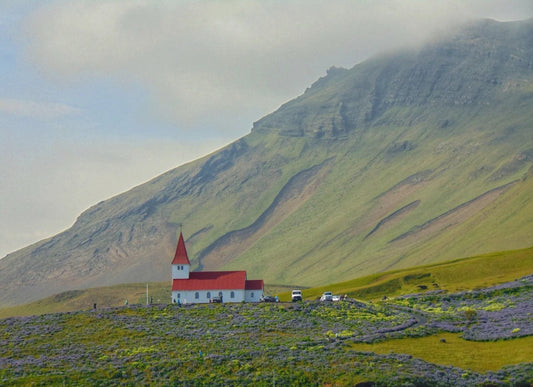 Red farmhouse nestled in a lush green valley on Iceland’s South Coast