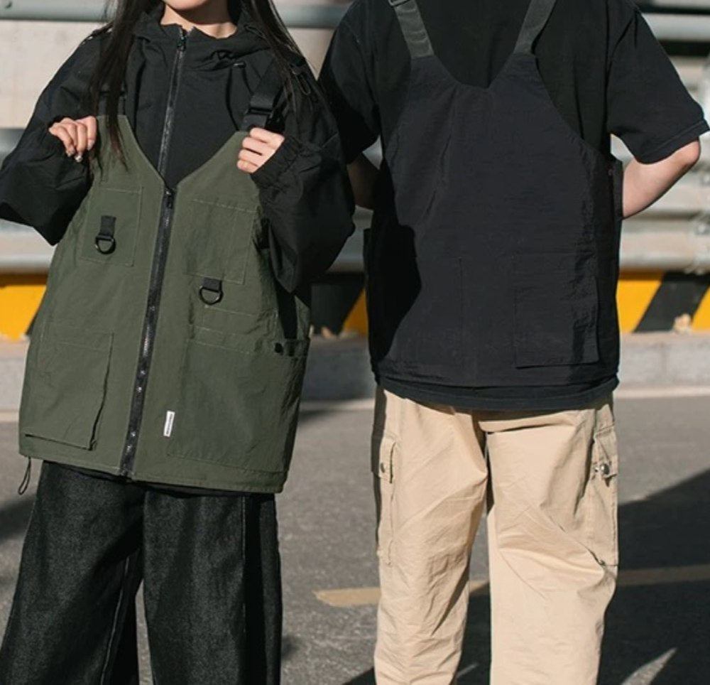 Two people from the waist down, one on the left wearing the 9902 Wearable Crossbody Bag transformed into a dark olive green vest, and another on the right wearing the black version, highlighting the product in use.