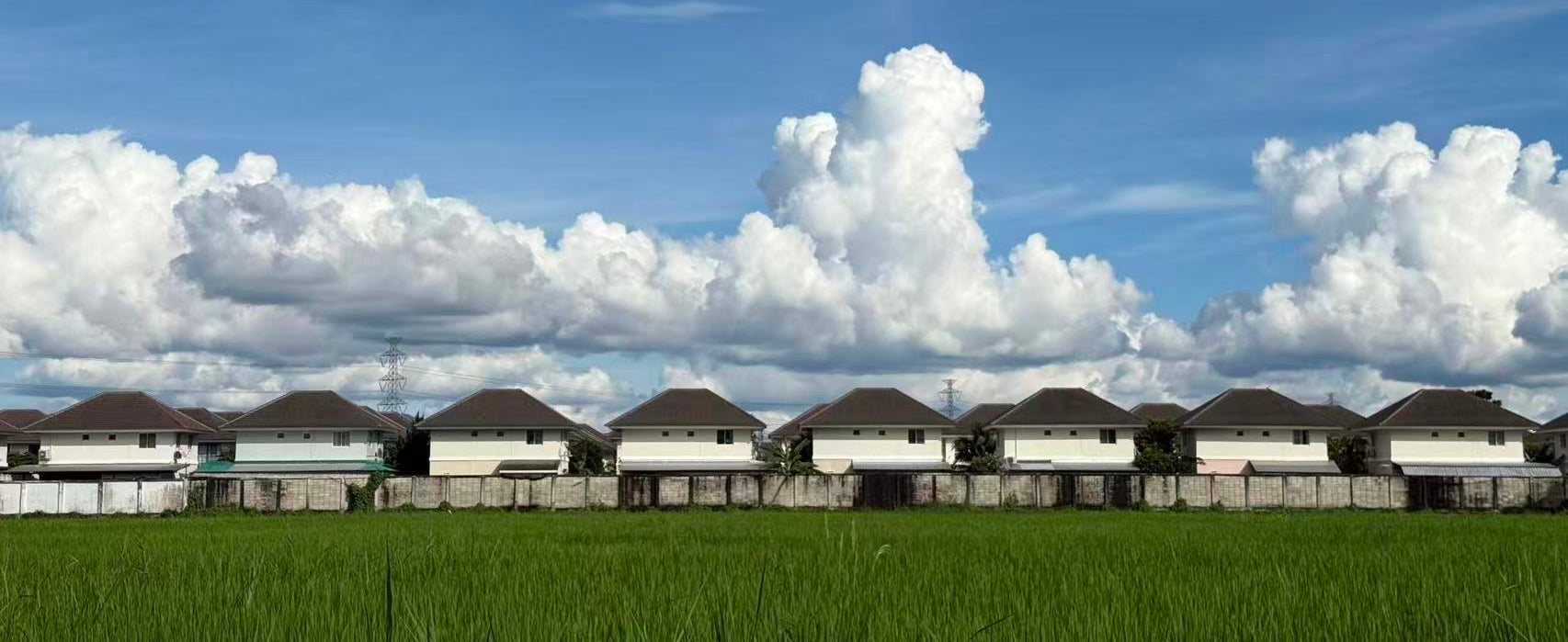 Wide landscape with houses under blue sky, representing the full collection of travel backpacks for every journey