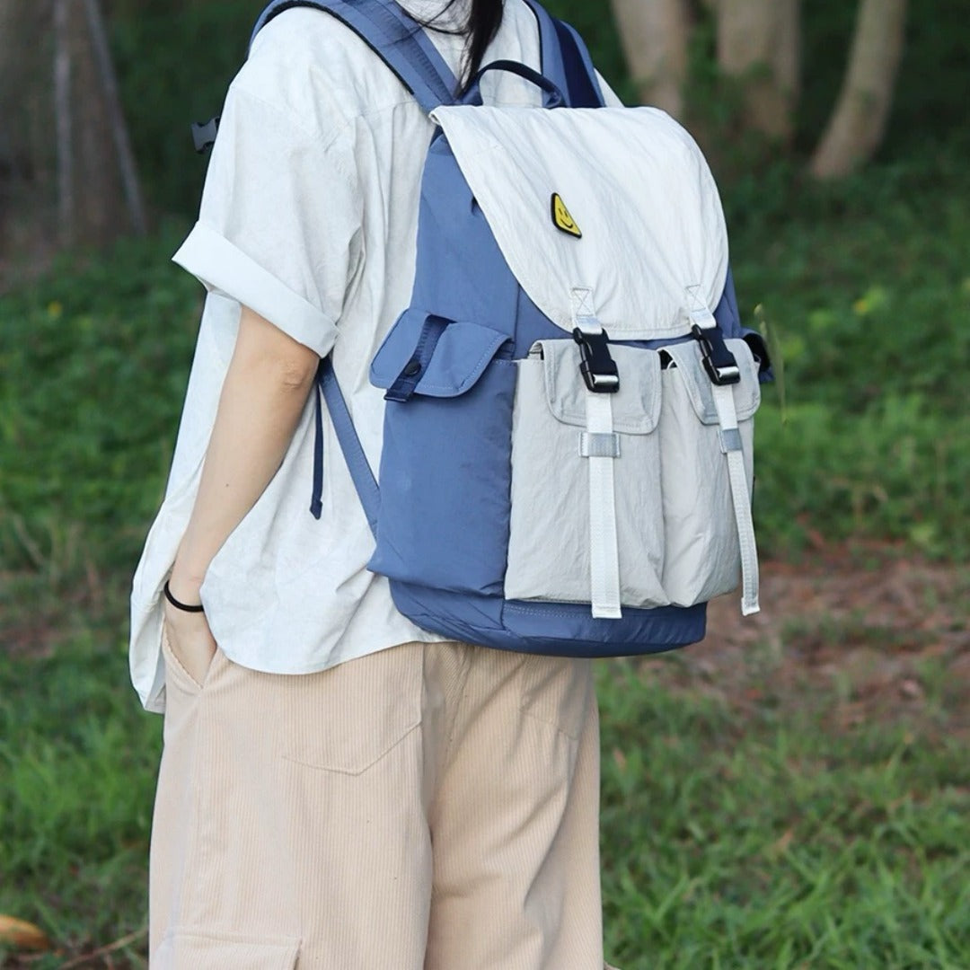 Person wearing blue-gray lightweight waterproof backpack showing comfortable fit and stylish mixed-color design for urban commuting