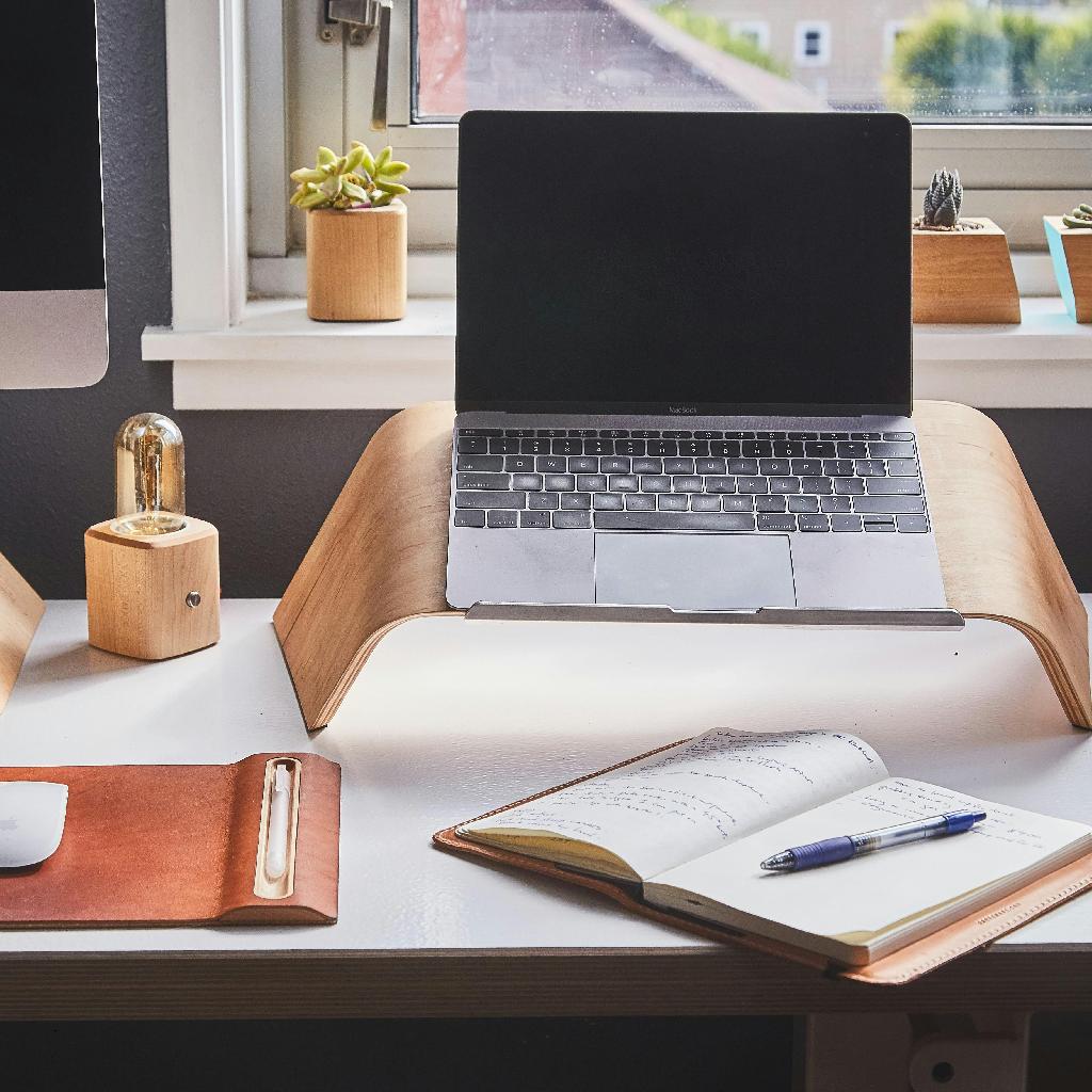laptop on ergonomic stand with notebook showing sustainable digital nomad workspace setup for long-term remote work lifestyle