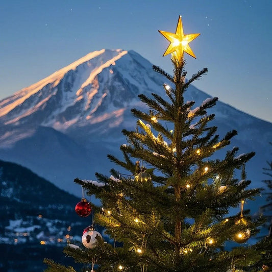 Illuminated Christmas tree with golden star and ornaments against snow-capped mountain at dusk