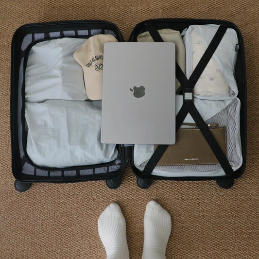 Minimalist packing for digital nomad lifestyle with organized suitcase, MacBook, and packing cubes for frequent moves between cities like Mexico City