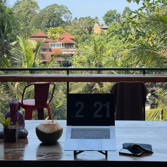 Digital nomad working on laptop at tropical outdoor workspace with palm trees and coconut, perfect nomad backpack setup for remote work