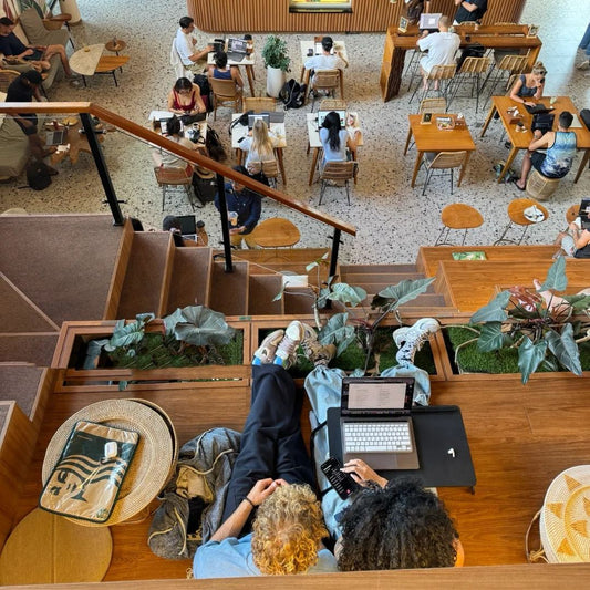 Overhead view of digital nomads with laptops working at contemporary coworking space in Bali, showcasing nomad backpacks and remote work setup