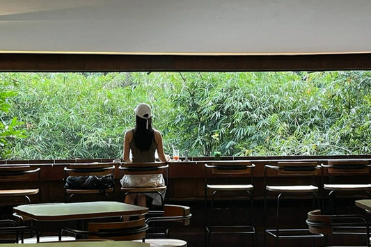 Digital nomad with cap working on laptop in modern cafe workspace, ideal environment for nomad backpack users