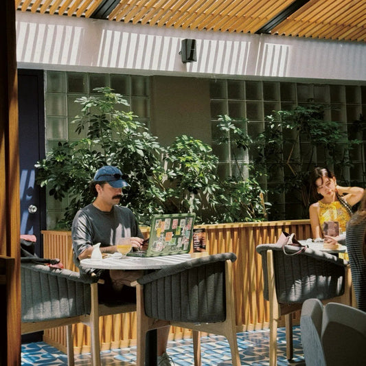 Digital nomads coworking at café table with green plant wall in Mexico City ideal setting for meeting friends