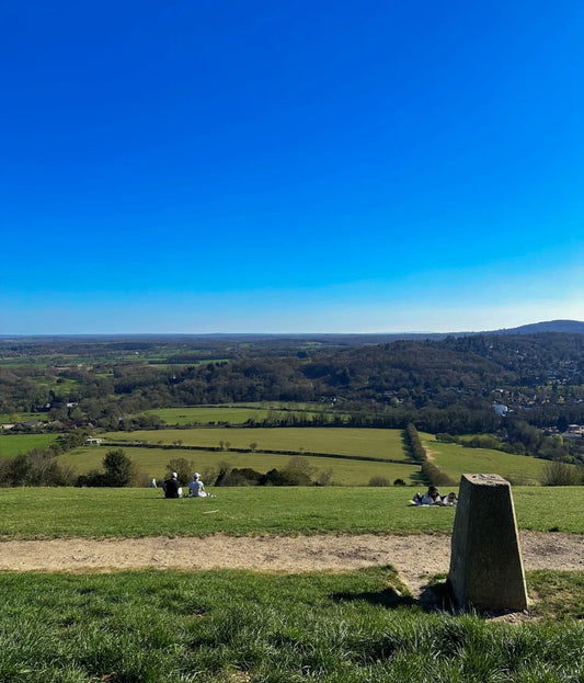 Panoramic view from Box Hill summit with green fields and clear blue sky, seen during a spring hike in the Surrey Hills