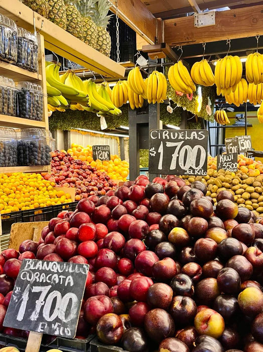 Cherries and apples stacked at a colorful fruit stall in Santiago’s La Vega market