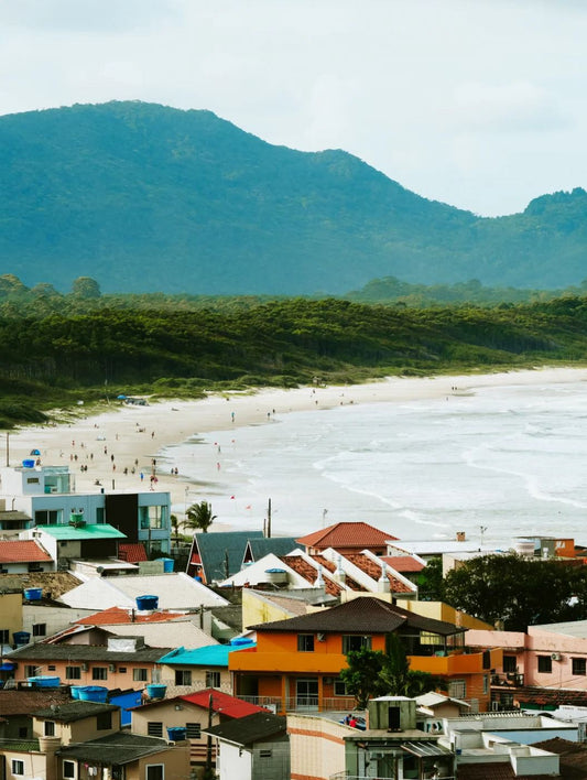 Overlooking Barra da Lagoa beach and colorful rooftops in Florianópolis, with green mountains in the background