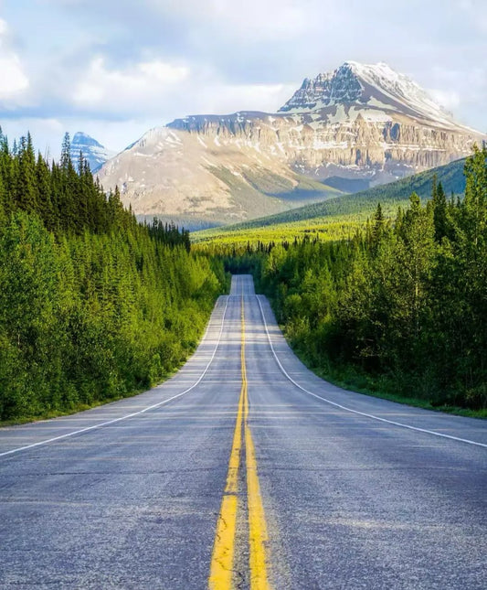 Scenic drive along Icefields Parkway with open road leading to distant mountains in Banff