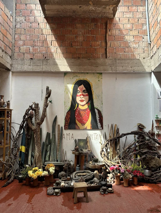  Indoor altar with cactus, flowers, and a painted portrait of an indigenous woman on the wall