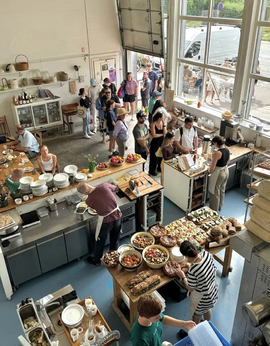 Busy morning at Lille Bakery in Copenhagen with an open kitchen and customers lining up for fresh sourdough and seasonal dishes