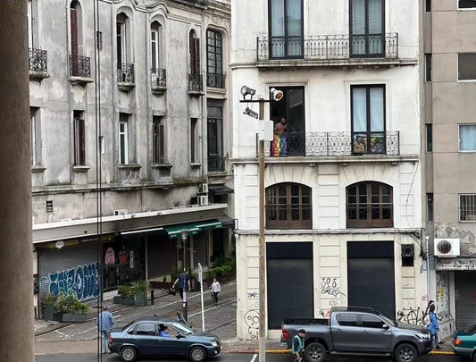 Street view of old Montevideo buildings with a man standing on a balcony.