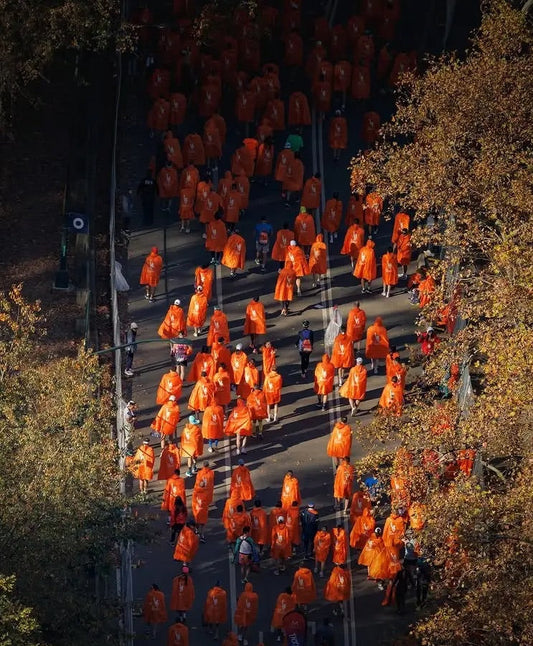 Aerial view of runners flooding through Brooklyn during the 2025 NYC Marathon, showcasing the scale and energy of the race.