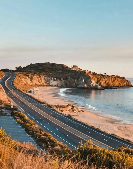 Scenic view of the Pacific Coast Highway curving along California’s coastline with golden cliffs and calm ocean