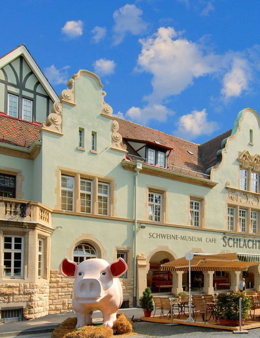 Exterior view of Schweinemuseum in Stuttgart with pastel green facade and pink pig-shaped vehicle