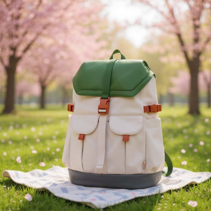 7708 stylish waterproof backpack positioned on picnic blanket under blooming cherry blossoms, showcasing outdoor leisure lifestyle and natural setting compatibility