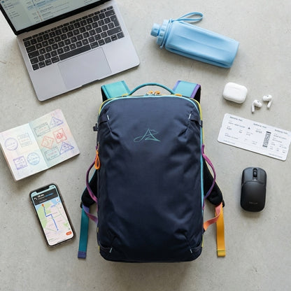 8805 navy 28L travel backpack flat lay on gray concrete with MacBook, passport, iPhone map app, AirPods, boarding pass, wireless mouse and blue silicone foldable water bottle, digital nomad travel essentials