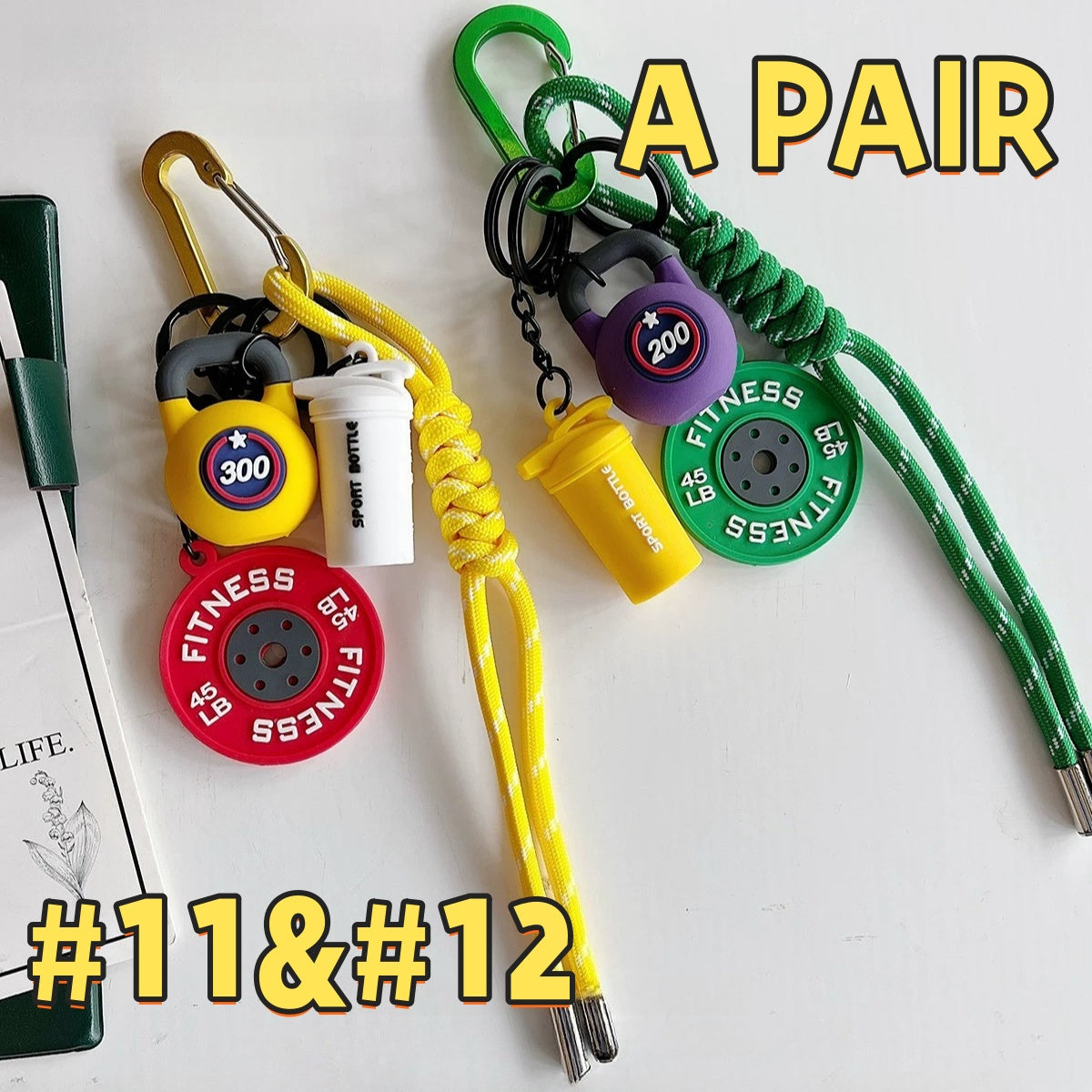 Colorful fitness keychain pair AC#11 and AC#12 in yellow and green, showing FITNESS weight plates, kettlebells, and Sport Bottle tags