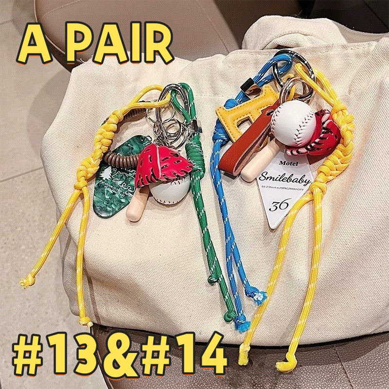 Baseball sports keychain pair AC#13 and AC#14 with baseball gloves, bats, balls, motel cards, and colorful braided cords on canvas bag