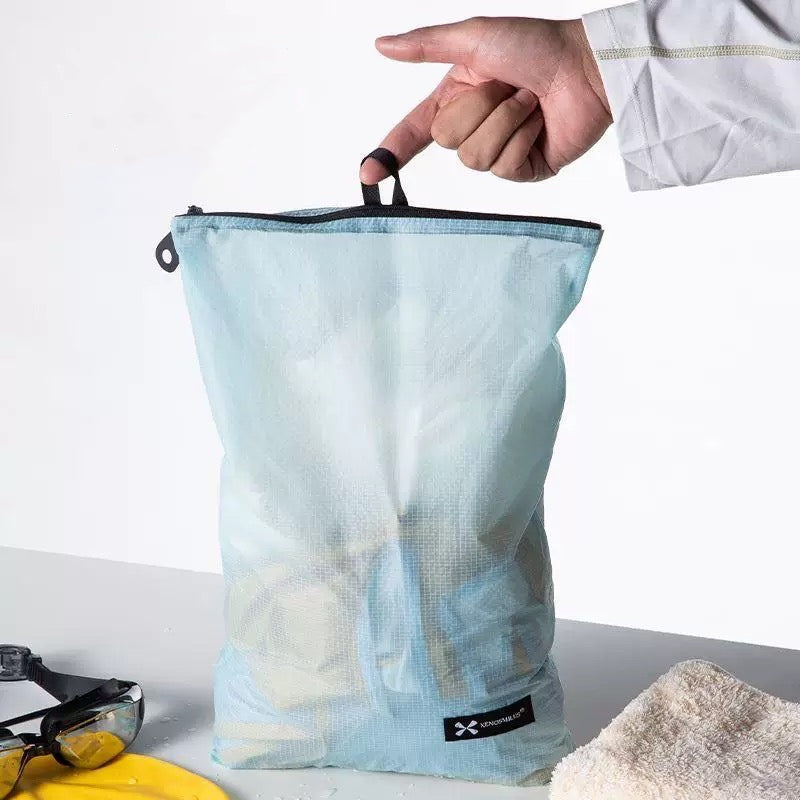 Hand holding BackpackBeat waterproof wet dry bag by top loop showing easy carry design and lightweight build