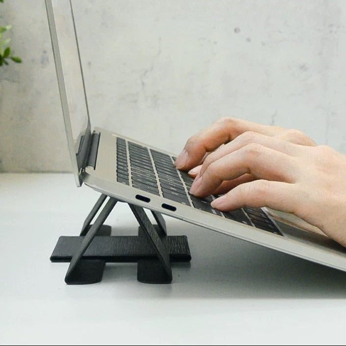 Person typing on MacBook elevated by BackpackBeat 1103 foldable laptop stand on white desk